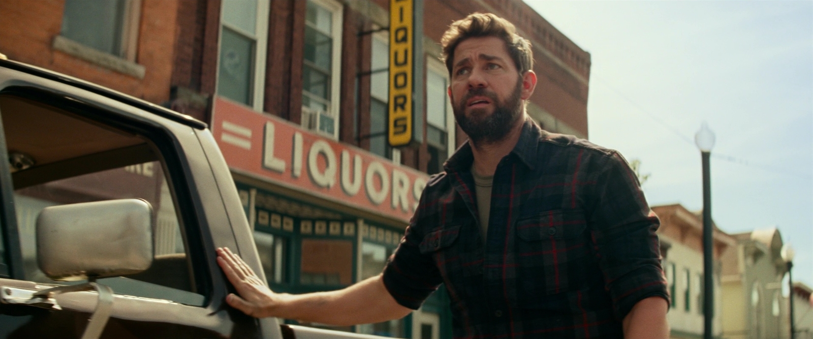 a man standing next to a truck in front of a liquor store