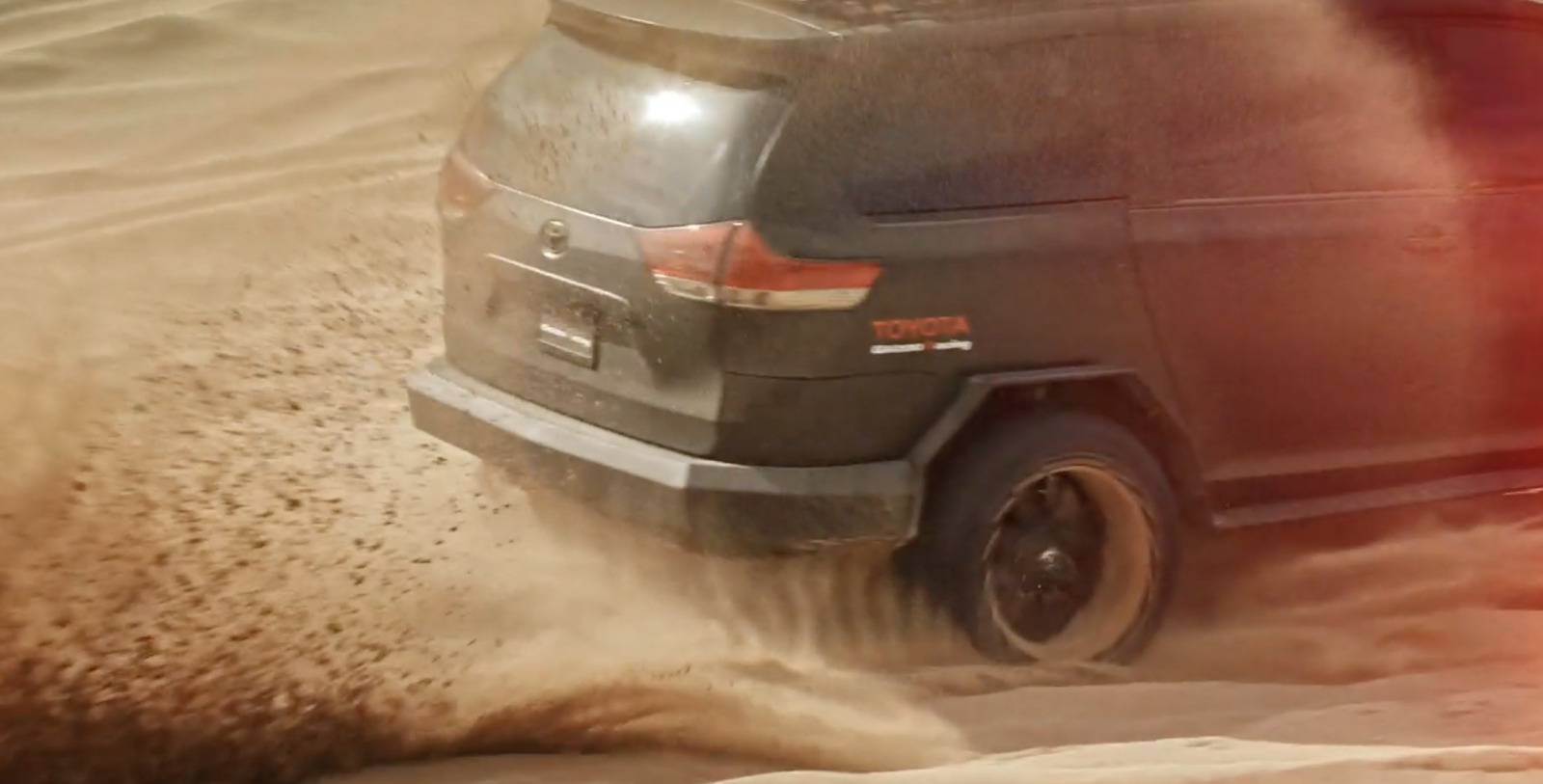 a black suv driving through the sand in the desert