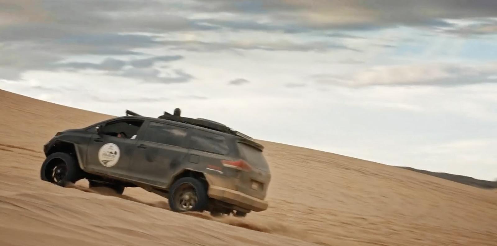 a vehicle driving through the desert on a cloudy day