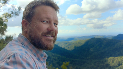 a man with a beard standing on top of a mountain