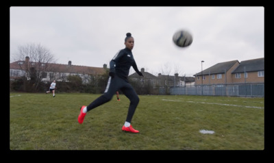 a woman kicking a soccer ball on top of a field