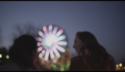 two women standing next to each other in front of a fireworks display