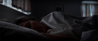 a woman laying in bed under a blanket