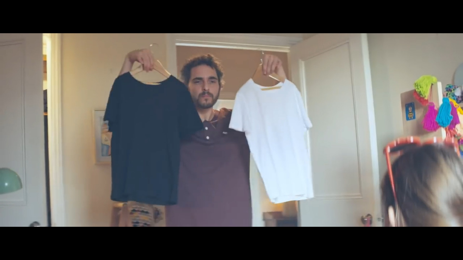 a man standing in front of a door holding two shirts