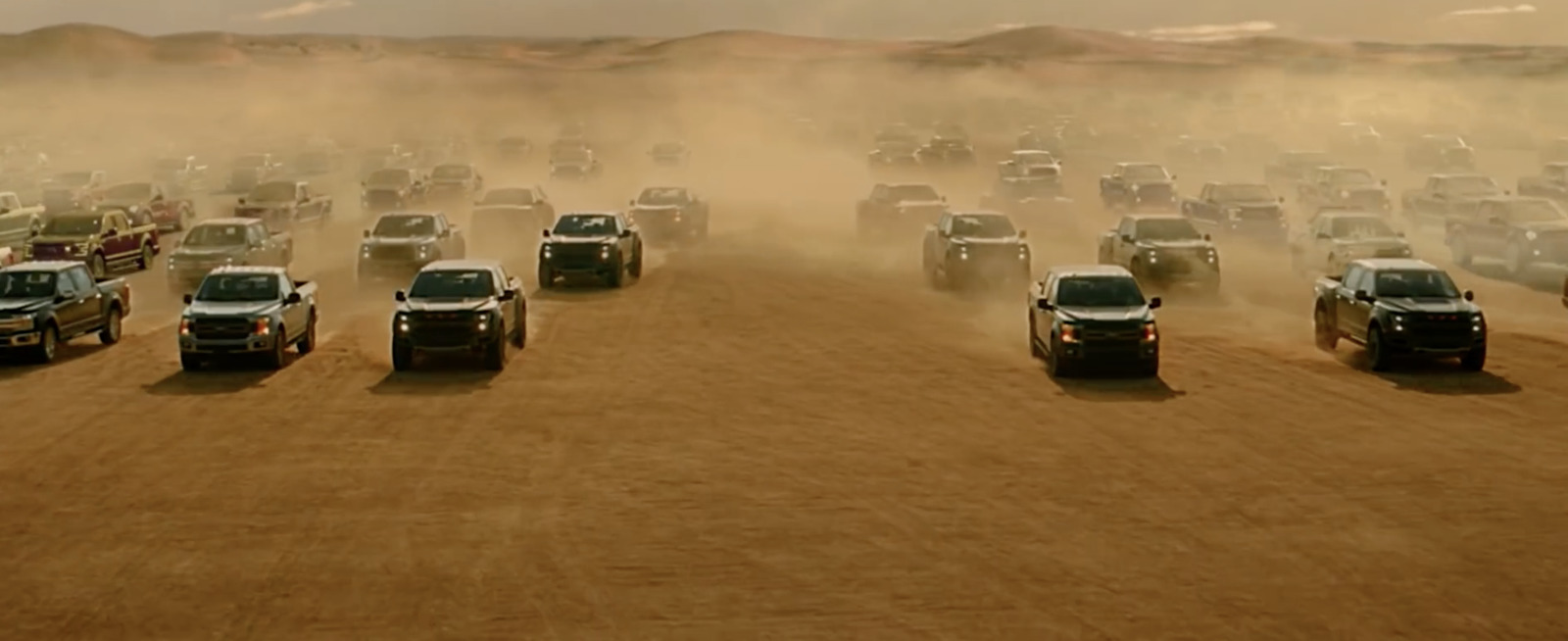 a large group of trucks driving down a dirt road