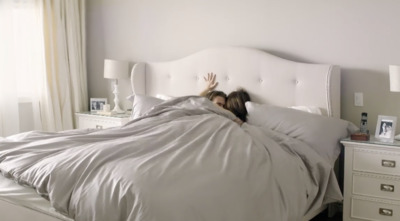 two girls laying in a bed with a white headboard