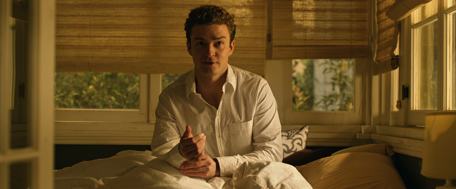 a man in a white shirt sitting on a bed