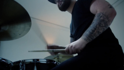 a man with tattoos playing drums in a room