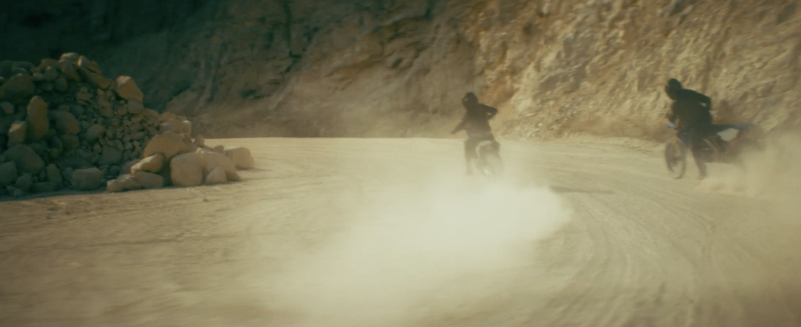 a couple of people riding bikes down a dirt road