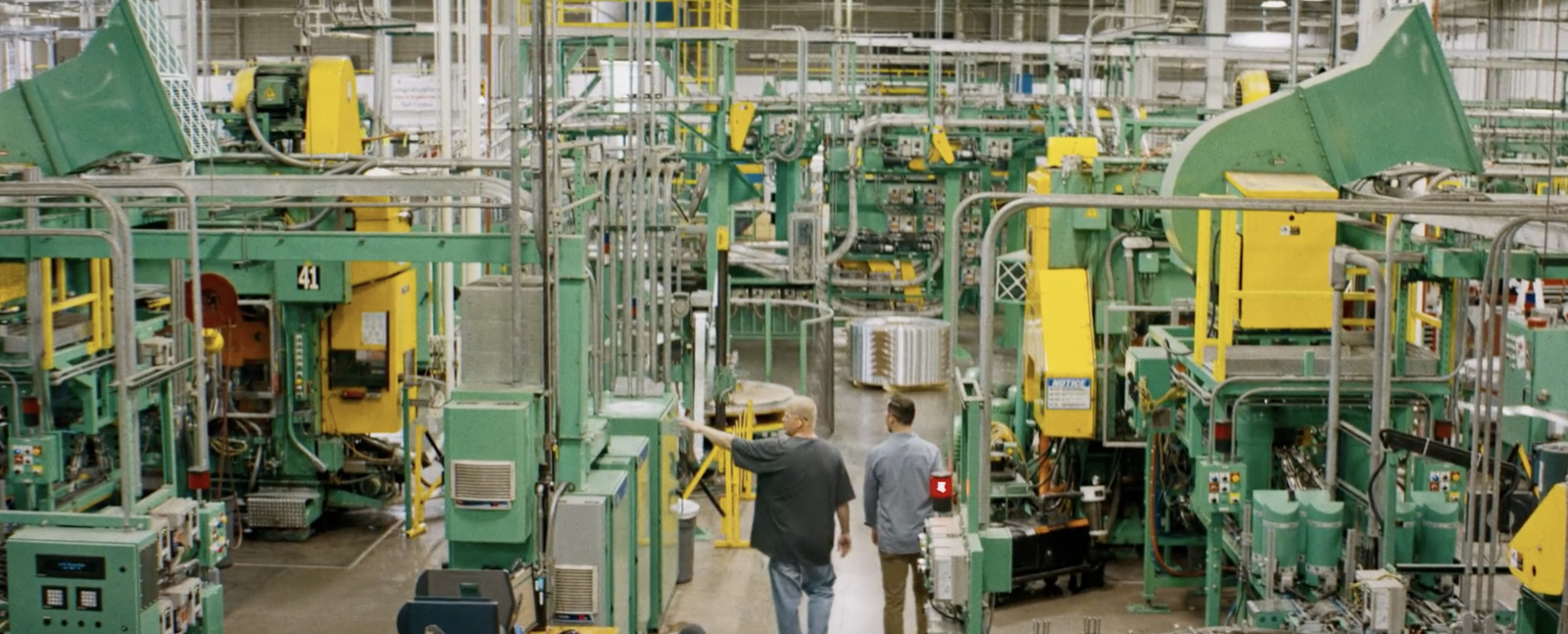 two men walking through a factory with machinery