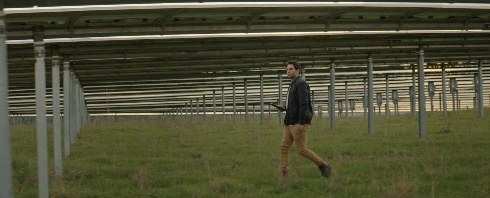 a man walking through a field next to a metal structure