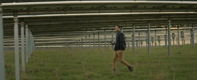 a man walking through a field next to a metal structure