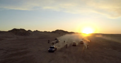 a group of cars driving down a dirt road