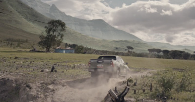 a truck driving down a dirt road in the mountains