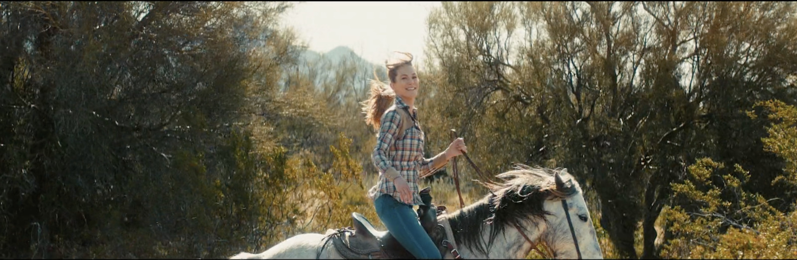 a woman riding on the back of a white horse