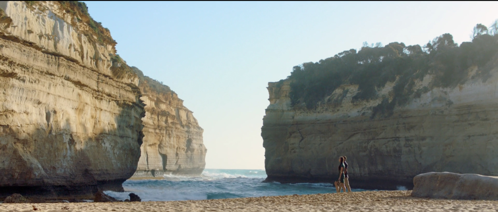 a person standing on a beach next to a cliff