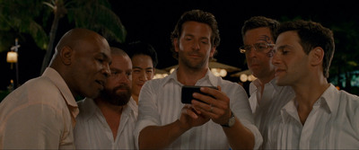 a group of men standing next to each other looking at a cell phone