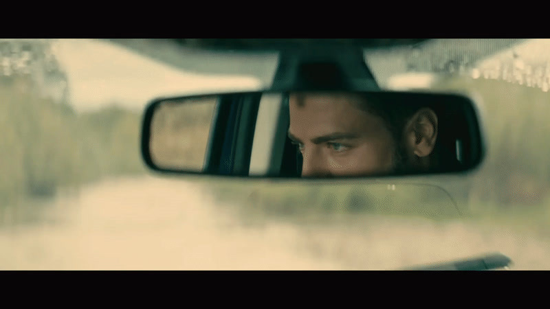 a man looking out of a car window in a rear view mirror