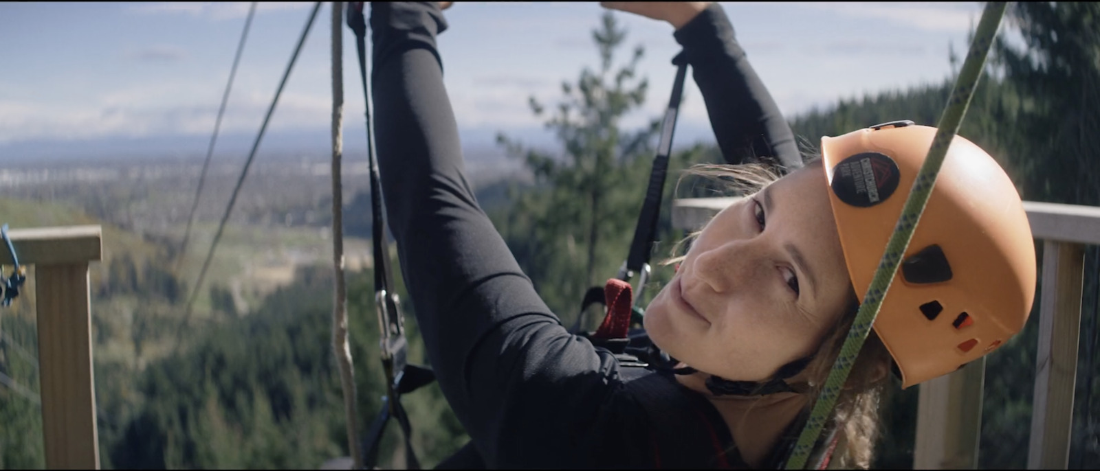 a young girl on a zip line with a helmet on