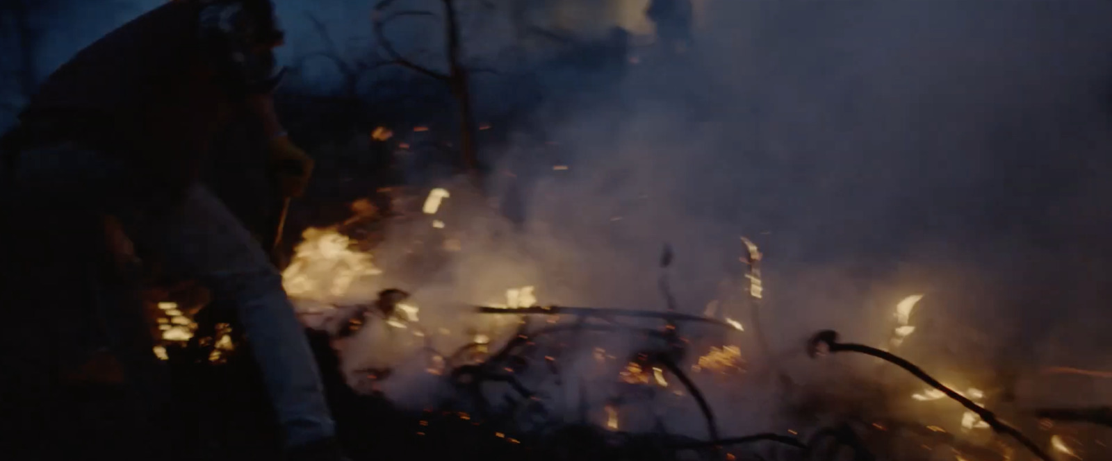 a man standing in front of a fire with lots of smoke coming out of it