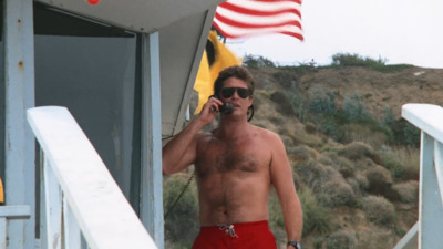 a shirtless man on a boat talking on a cell phone