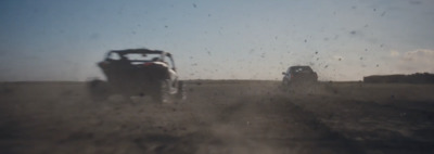 a couple of cars driving down a dirt road