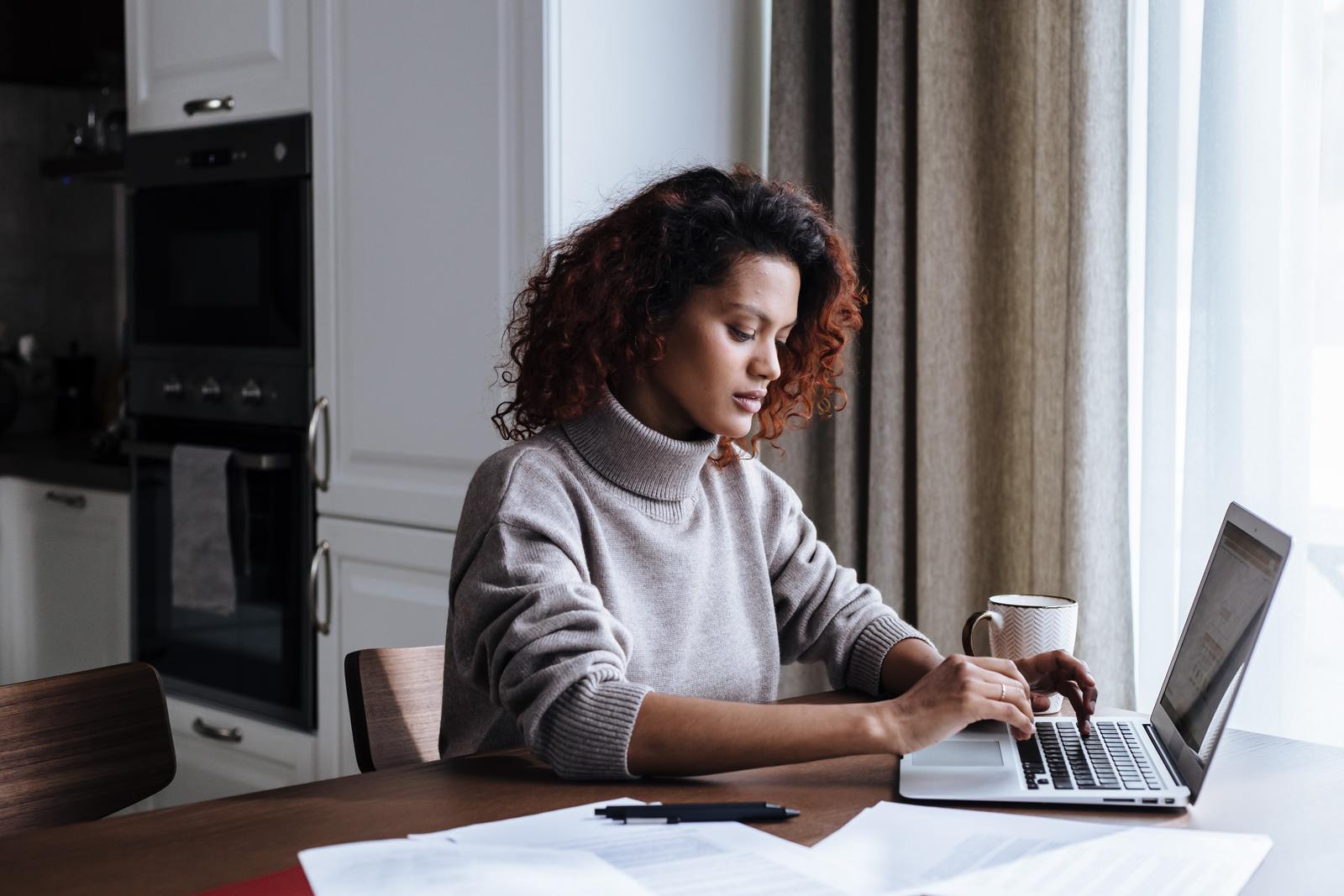 a woman sitting at a table using a laptop computer