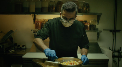 a man in a kitchen preparing food in a pan