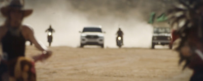 a truck driving down a dirt road next to a forest