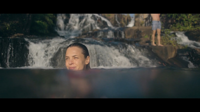 a woman in a pool of water with a waterfall in the background