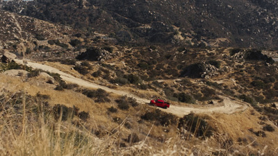 a red car driving down a dirt road