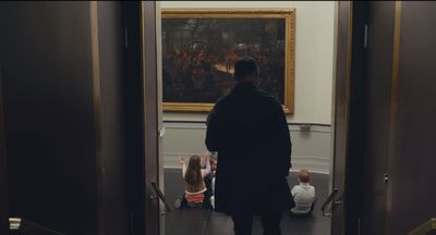 a man standing in front of a painting in a hallway