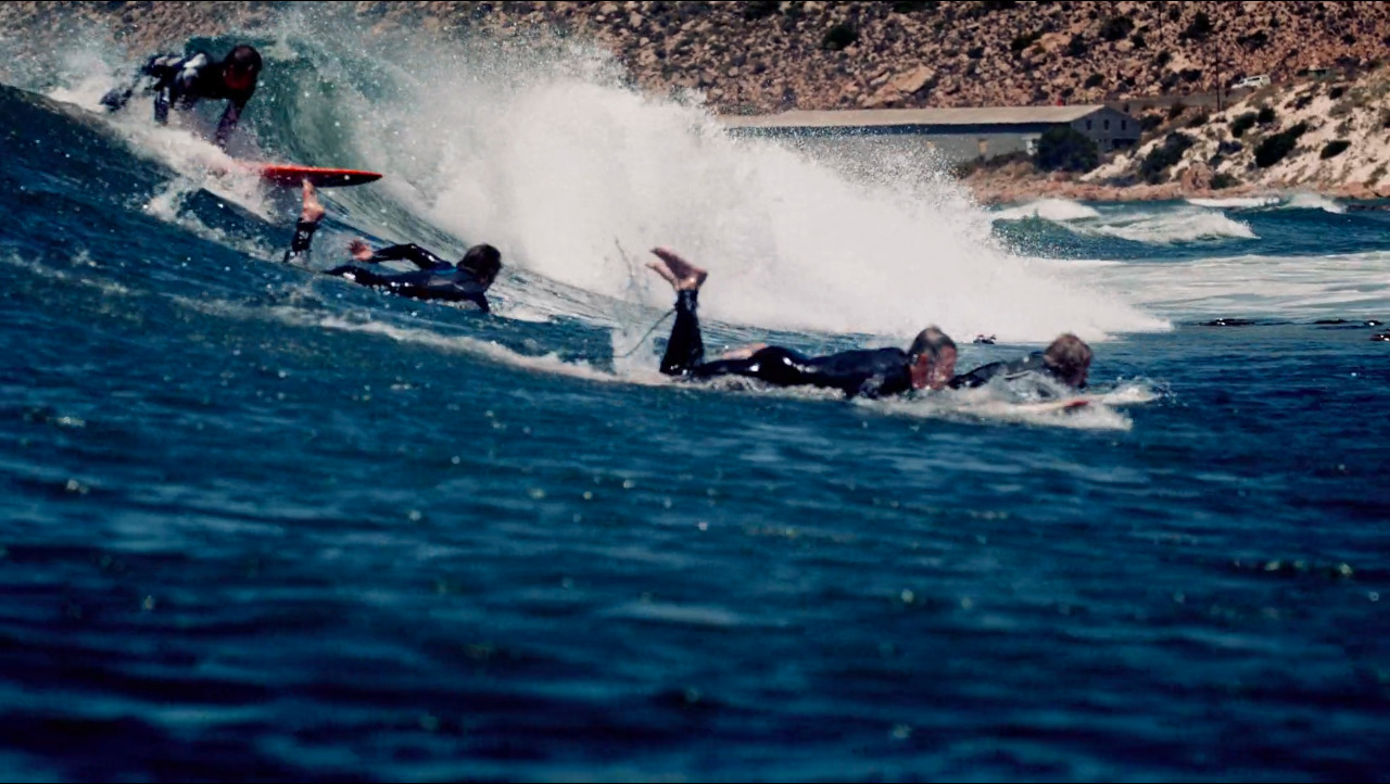 a group of people riding waves on top of surfboards