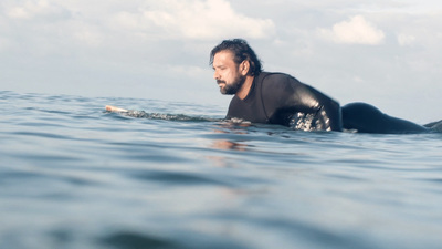 a man laying on a surfboard in the ocean