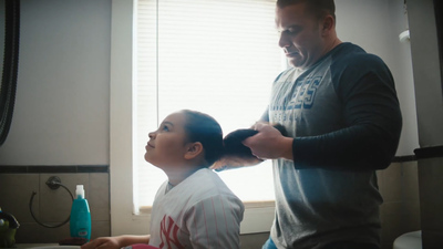 a man combing a young girl's hair in a bathroom