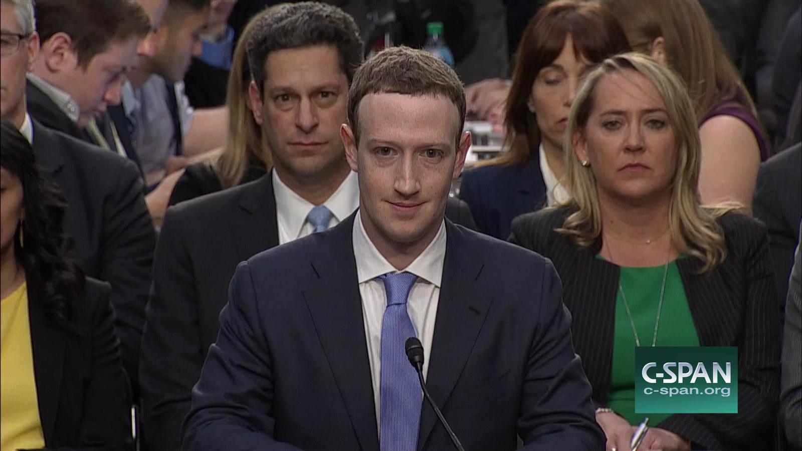 a man in a suit and tie sitting in front of a microphone