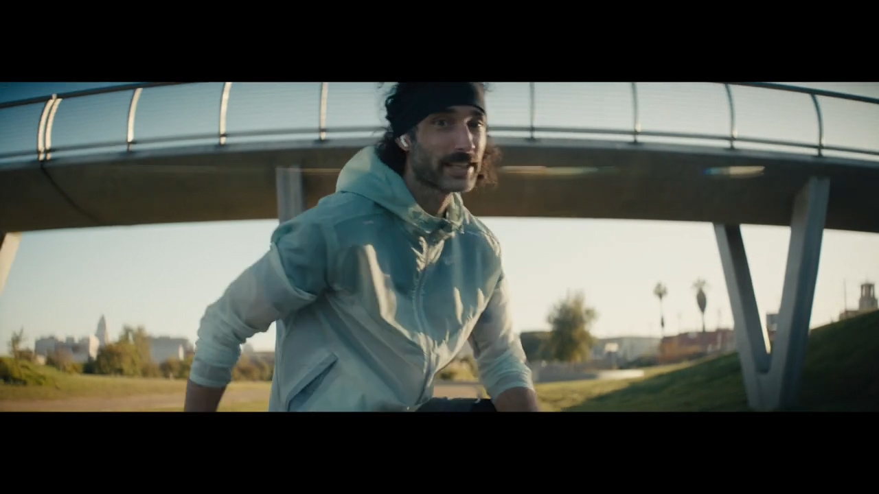 a man in a hoodie walking across a bridge