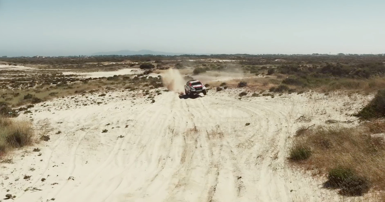 a truck driving down a dirt road in the desert