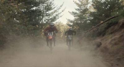 two people riding dirt bikes on a dirt road