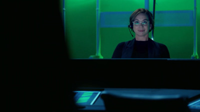 a woman with headphones on in front of a green screen