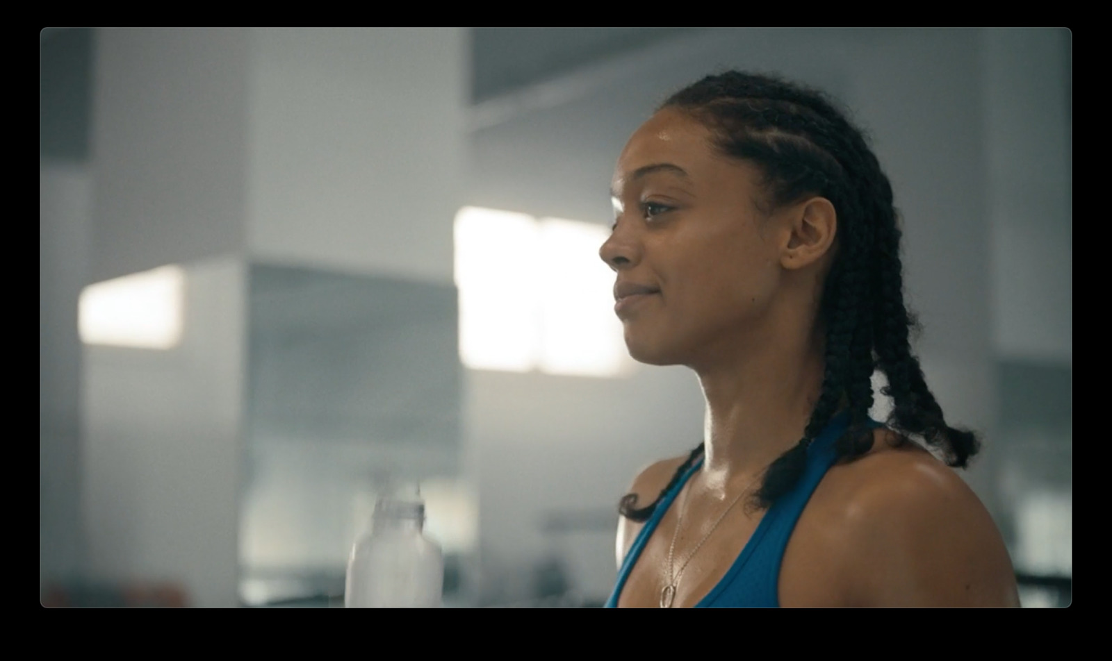 a woman in a blue tank top holding a glass of water