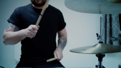 a man holding a drum stick in front of a drum set