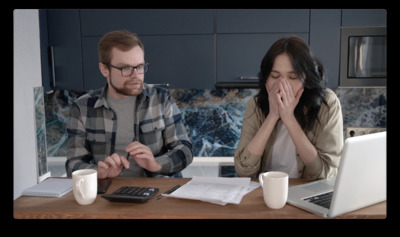 a man and woman sitting at a table in front of a laptop