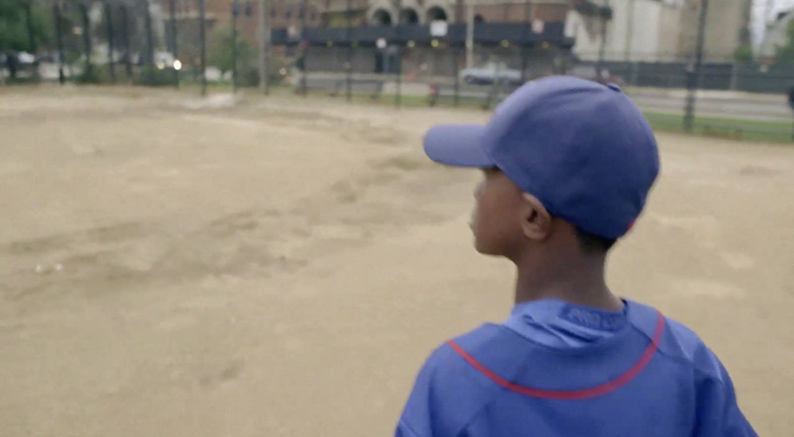 a young boy in a blue baseball uniform standing on a baseball field