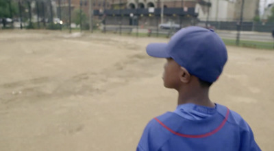 a young boy in a blue baseball uniform standing on a baseball field