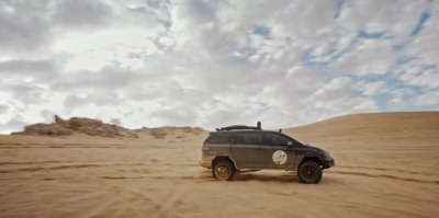 a vehicle driving through the desert on a cloudy day