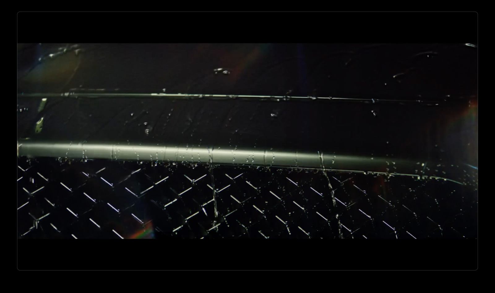 a close up of a metal fence with a rainbow in the background