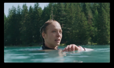 a woman in a body of water with trees in the background