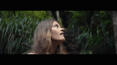 a woman standing in front of a lush green forest