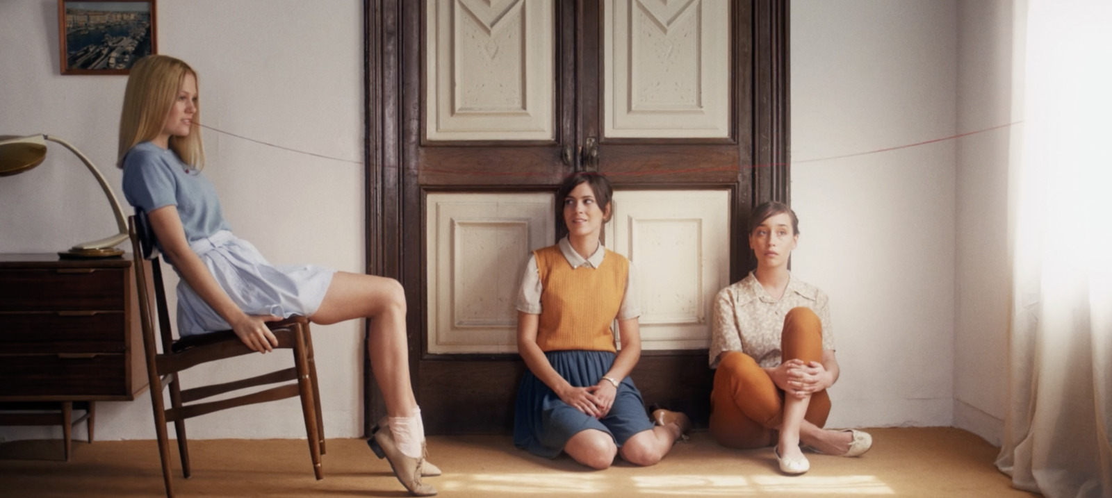 a group of women sitting on top of a wooden chair